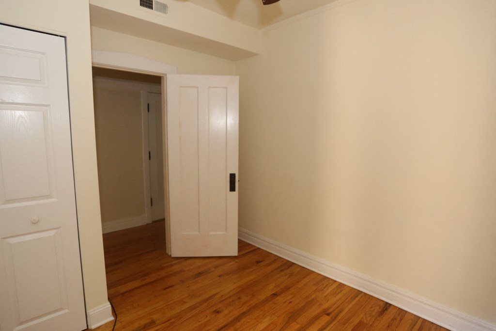 a bedroom with wood floors and a door to a closet