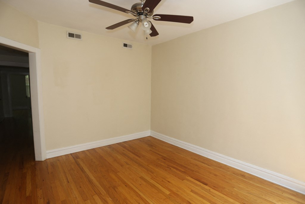 an empty living room with wooden floors and a ceiling fan