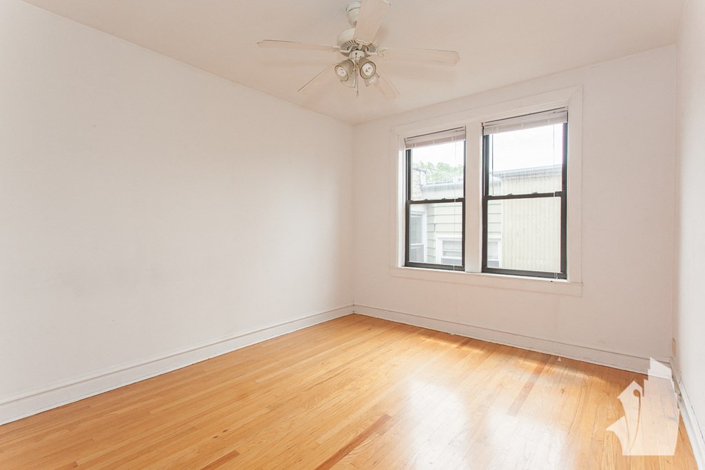 an empty room with wood floors and a ceiling fan