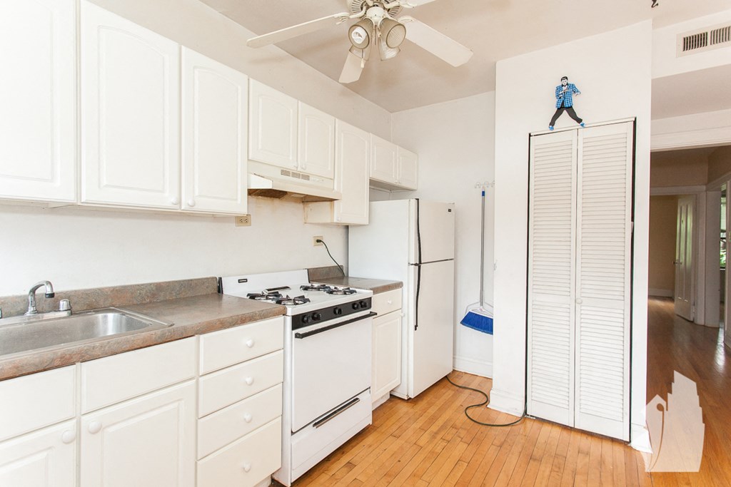 a kitchen with white cabinets and white appliances and a refrigerator