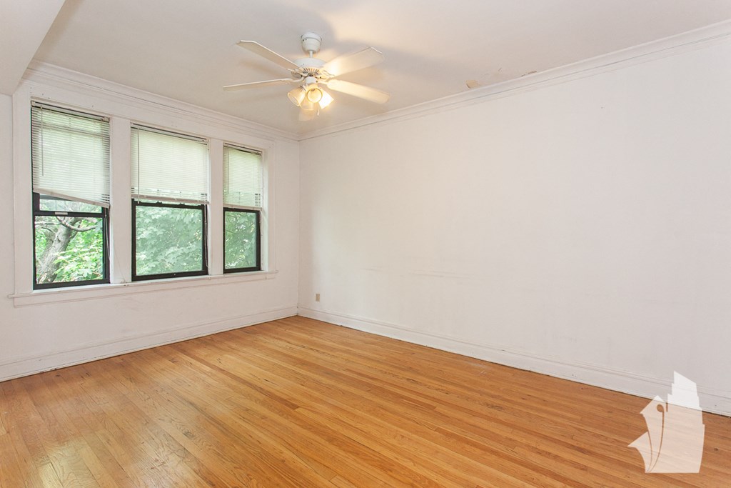an empty living room with wood floors and a ceiling fan