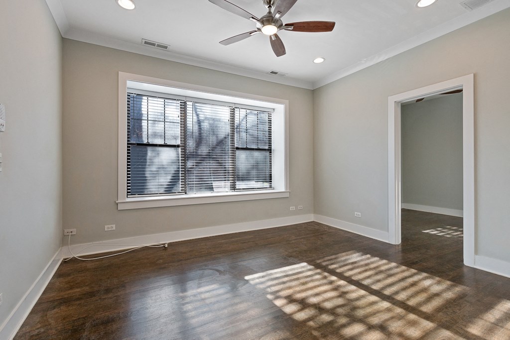 an empty living room with a window and a ceiling fan
