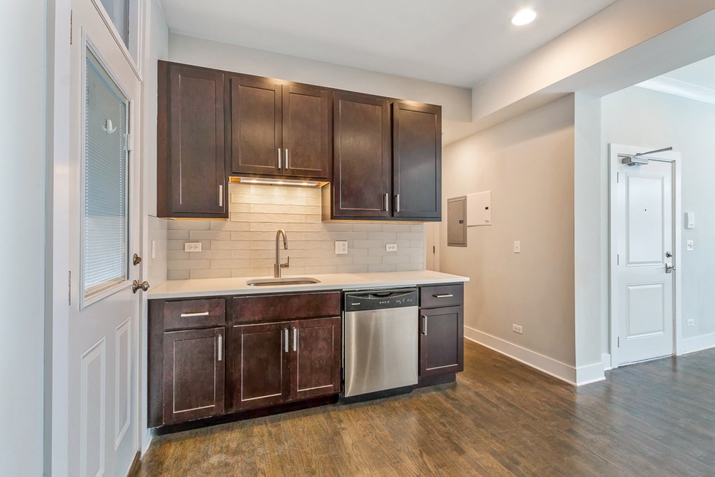 a kitchen with dark wood cabinets and a white counter top with a sink and a