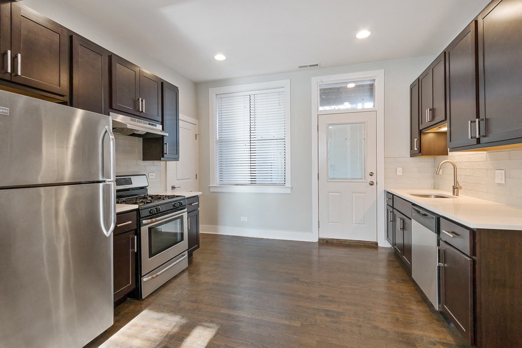an empty kitchen with stainless steel appliances and wooden cabinets