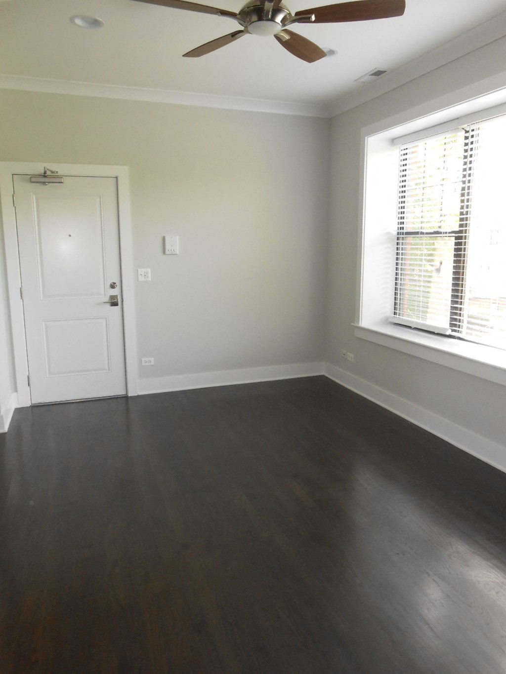 an empty living room with wood floors and a ceiling fan