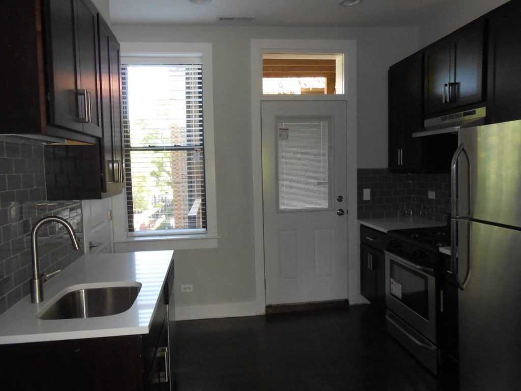 an empty kitchen with a white door and window