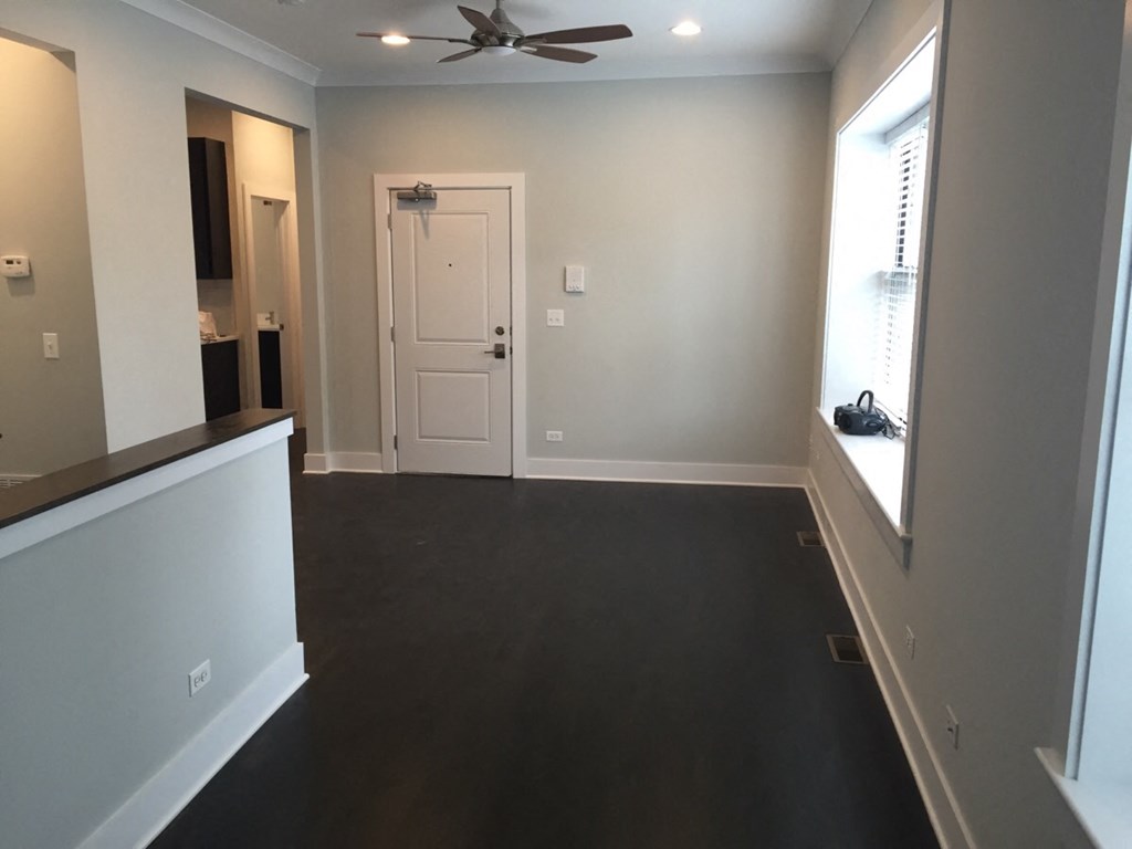 an empty living room with a ceiling fan and a window