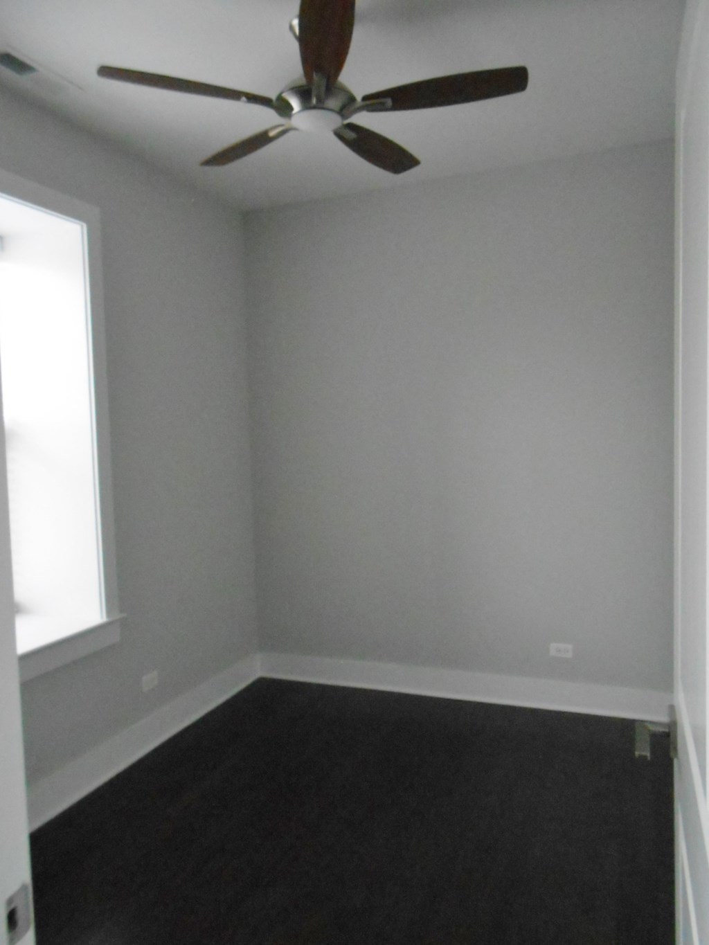 an empty room with a ceiling fan and a black floor