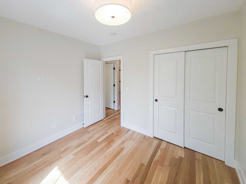 a bedroom with two closets and a hard wood floor