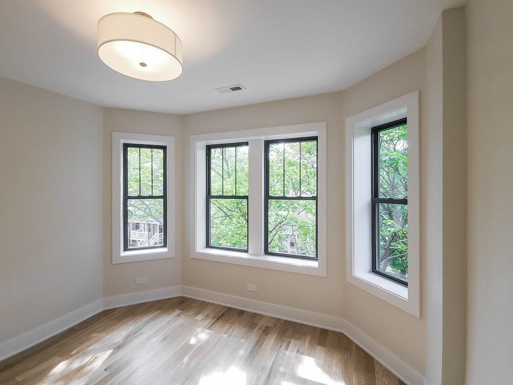 an empty living room with four windows and a hardwood floor