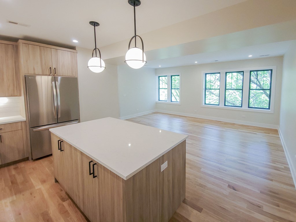 an empty kitchen with an island and a stainless steel refrigerator