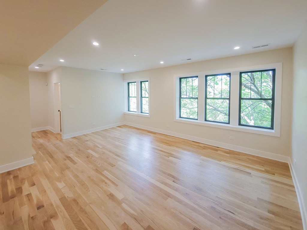 an empty living room with wooden floors and windows