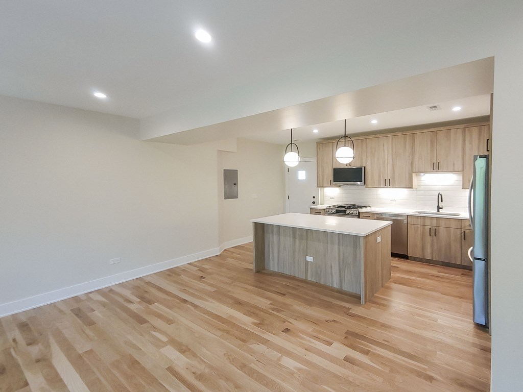 an open kitchen with a large island and wood flooring