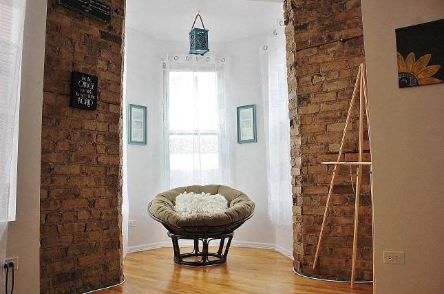 a living room with a chair and a brick wall