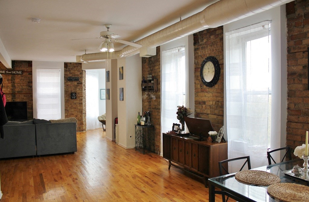 a living room with a wood floor and brick walls
