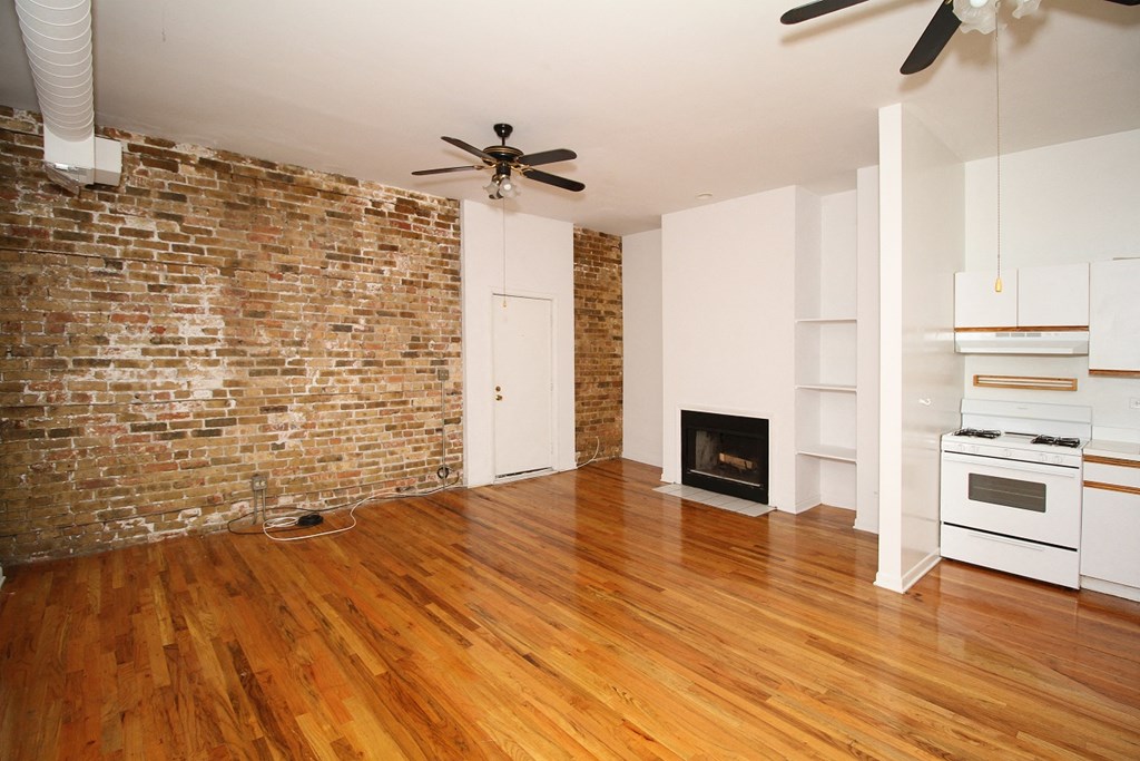 an empty living room with a brick wall and wooden floors