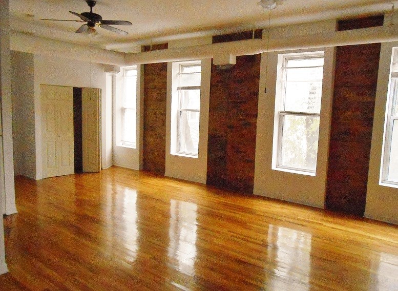 an empty living room with wooden floors and a ceiling fan