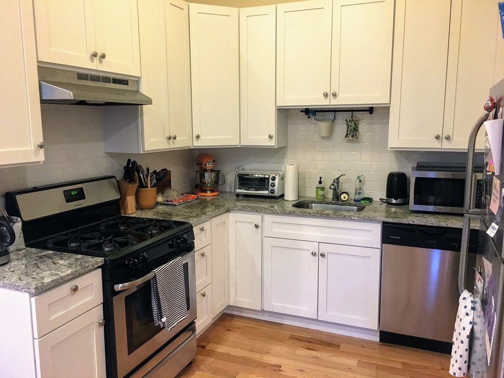 a white kitchen with stainless steel appliances and white cabinets