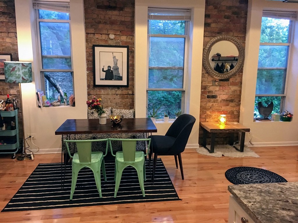 a dining room with a wooden floor and a table with green chairs