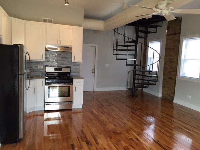 an empty kitchen with wood floors and a spiral staircase