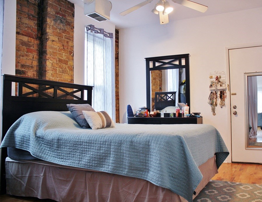a bedroom with a bed and a brick wall