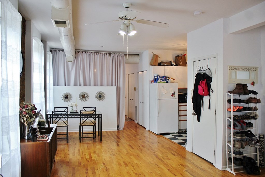 a living room and kitchen with a wood floor and a white refrigerator