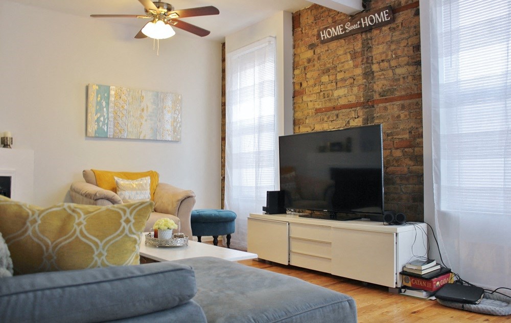 a living room with a brick wall and a television