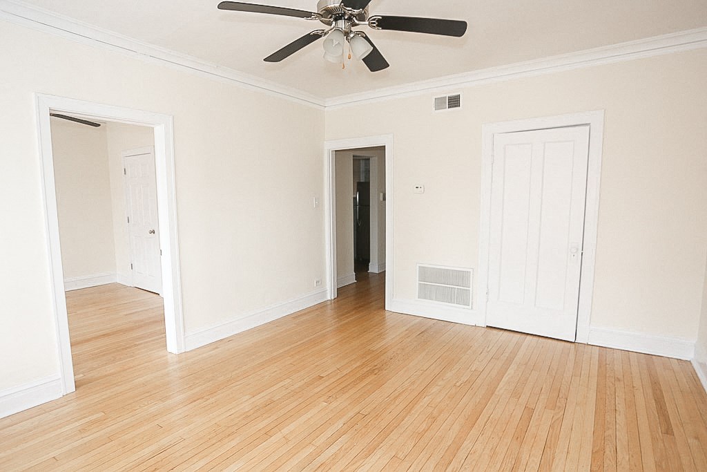 an empty living room with wood floors and a ceiling fan