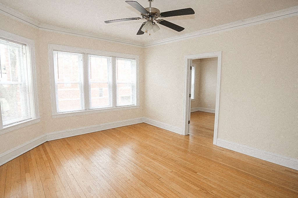 an empty room with a ceiling fan and wood floors