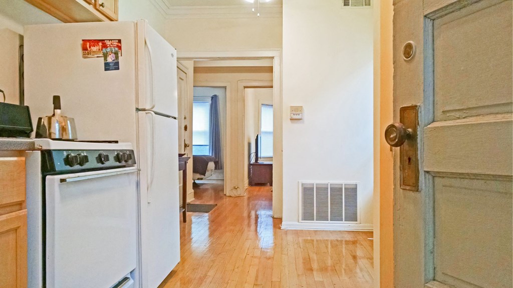 a kitchen with a stove and a refrigerator and a hallway to a living room