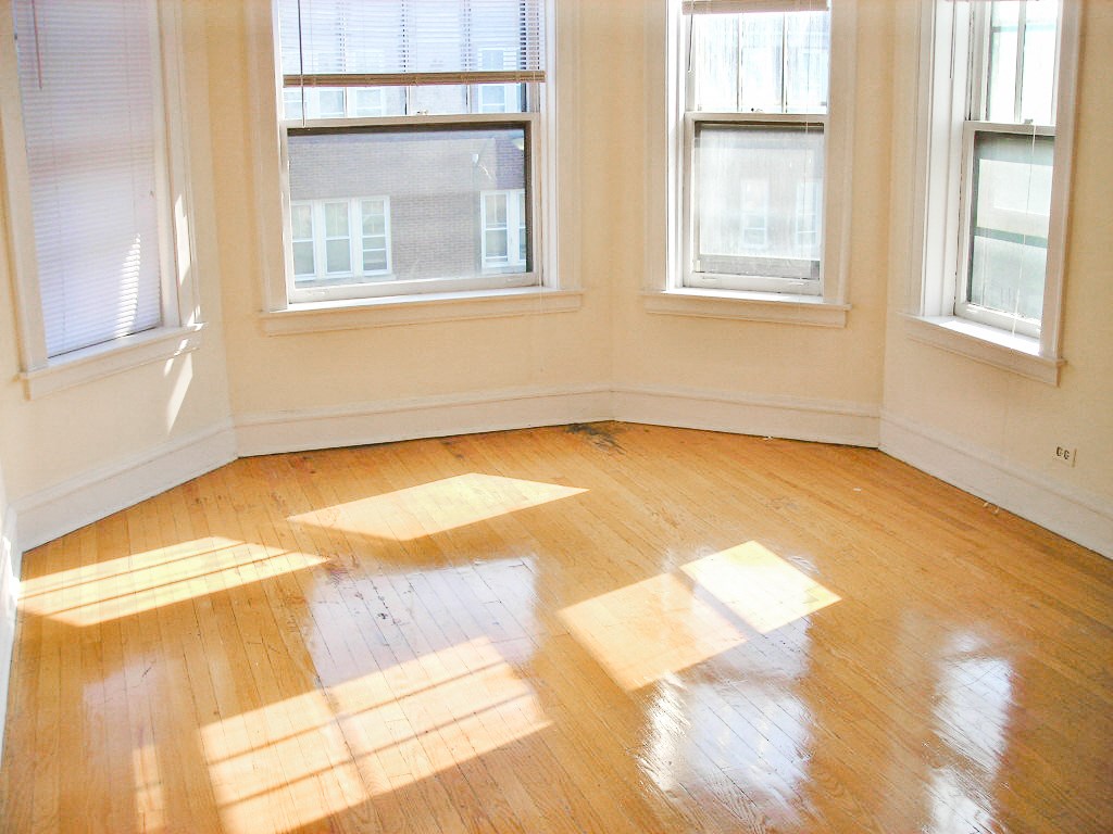 an empty room with sunlight shining through three windows