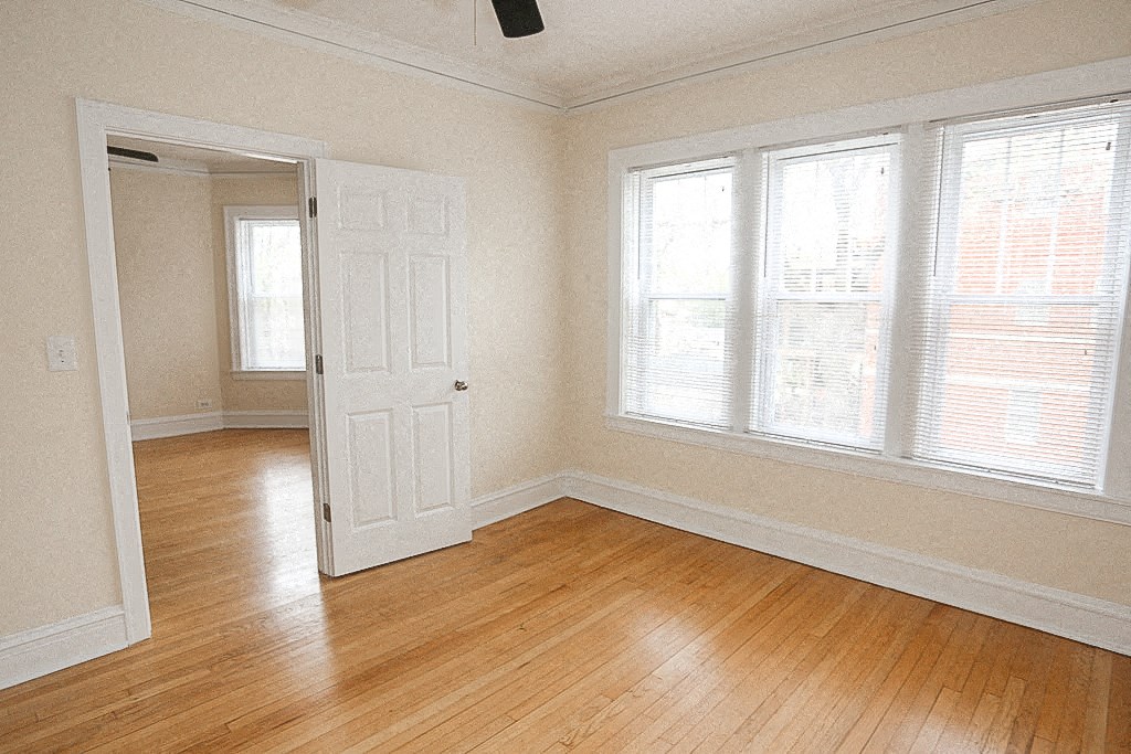 an empty room with a door and three windows
