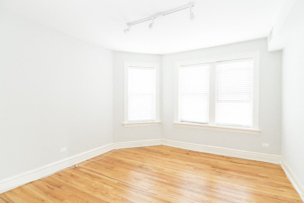 an empty room with a wooden floor and two windows