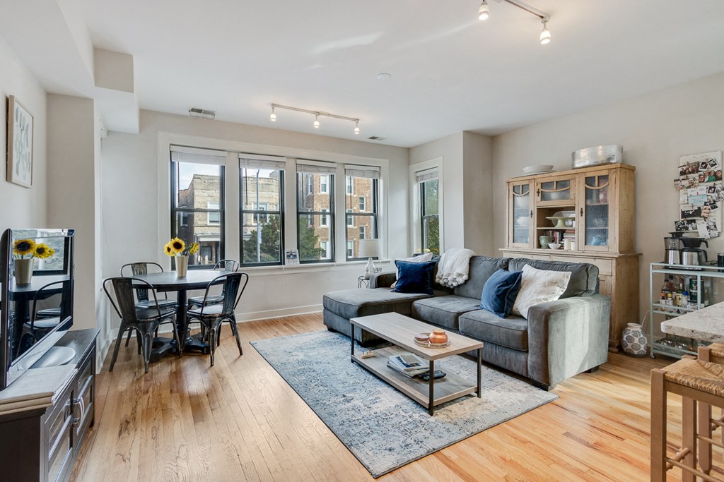 a living room with a couch and a dining room table and a large window