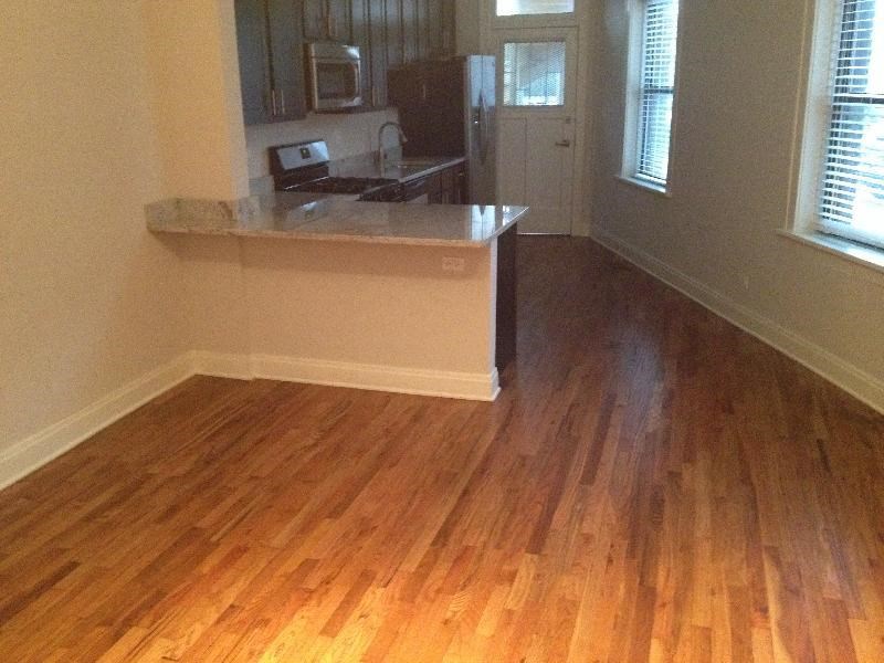a living room with a kitchen and a wooden floor