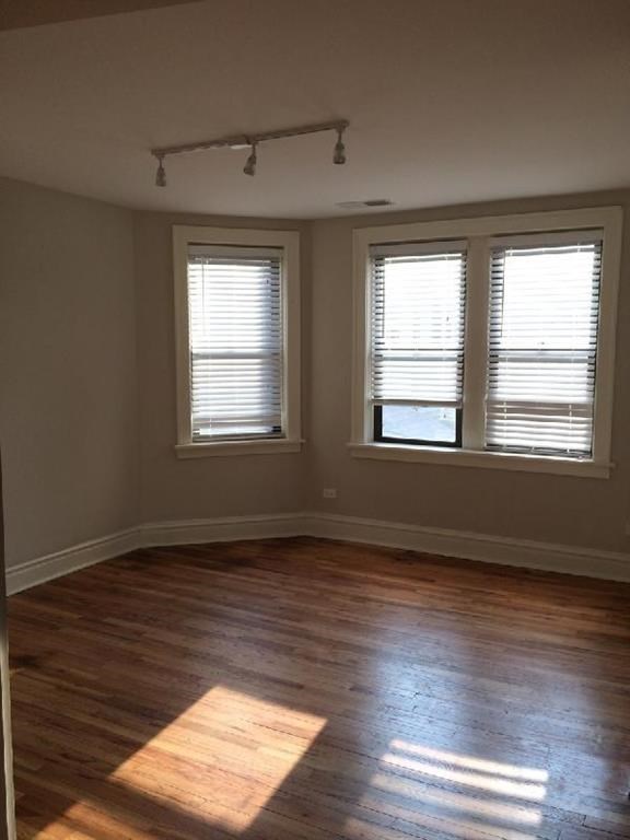 an empty room with a hard wood floor and two windows