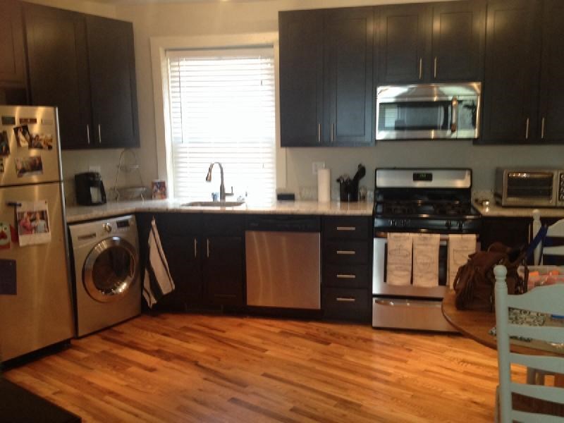 a kitchen with black cabinets and a wood floor