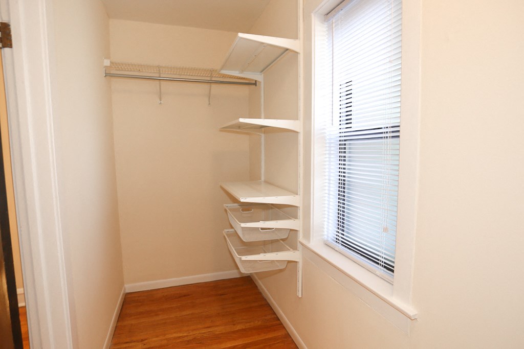 a walk in closet with shelves and a window