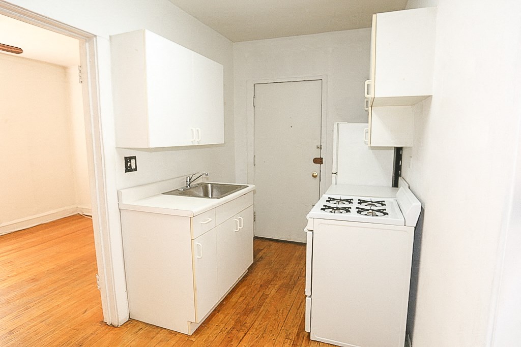an empty kitchen with a stove and sink and a refrigerator