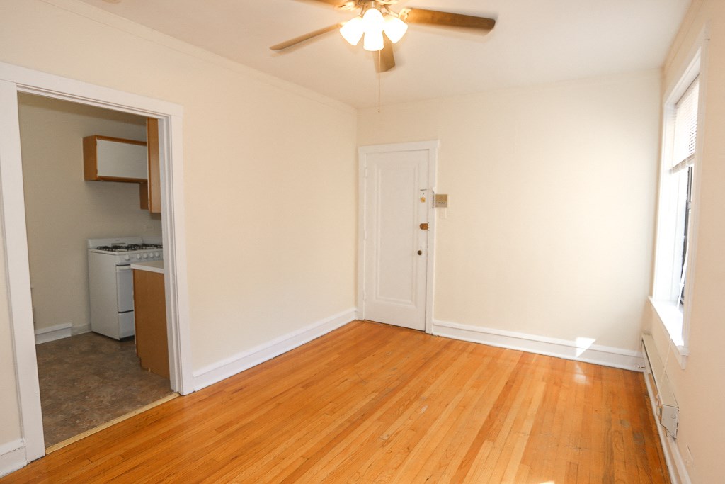 an empty living room with wood floors and a ceiling fan