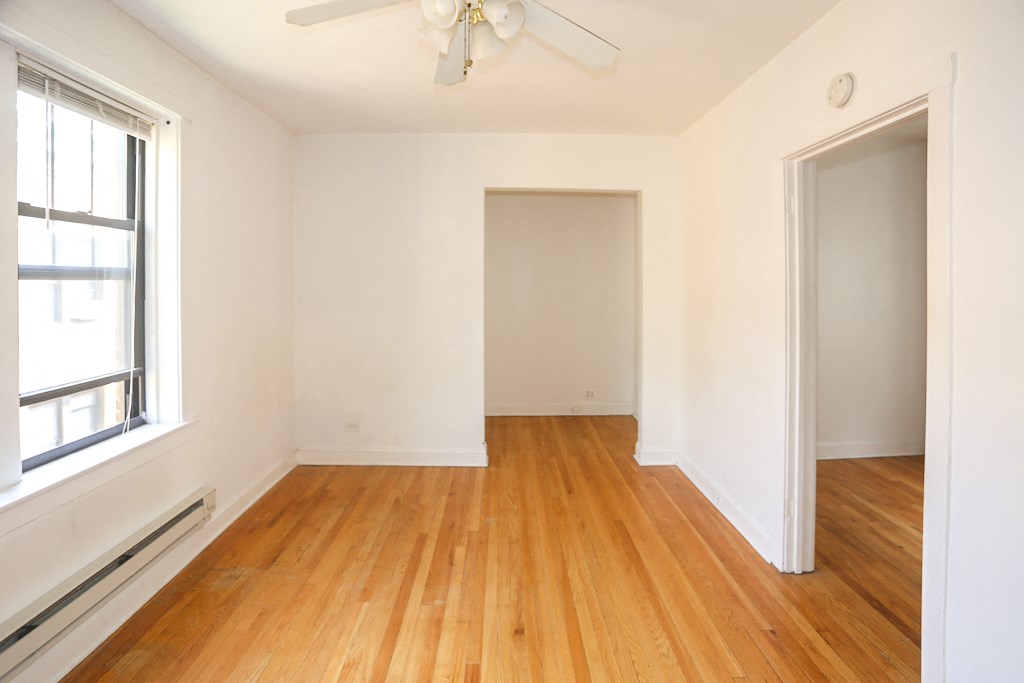 an empty room with wood floors and a ceiling fan