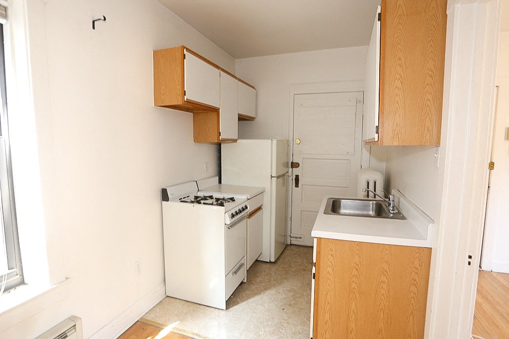 an empty kitchen with a stove refrigerator and sink