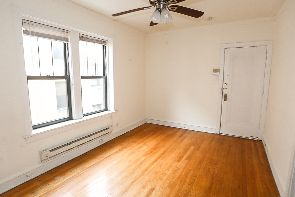 an empty room with wooden floors and a ceiling fan
