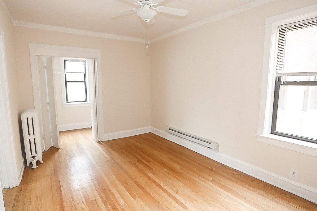 an empty room with wooden floors and a ceiling fan