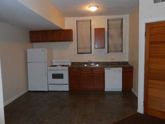 an empty kitchen with white appliances and wooden cabinets