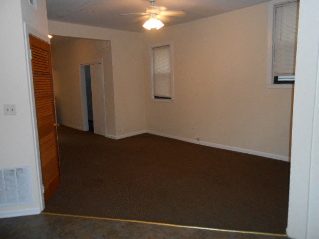 an empty living room with a ceiling fan