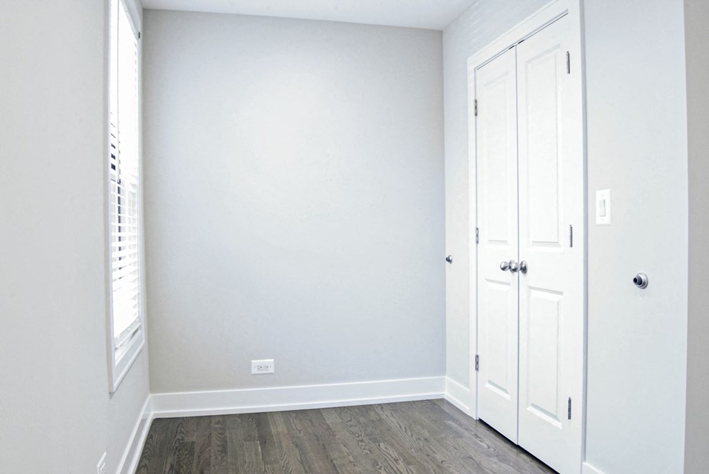 an empty room with white walls and wood floors
