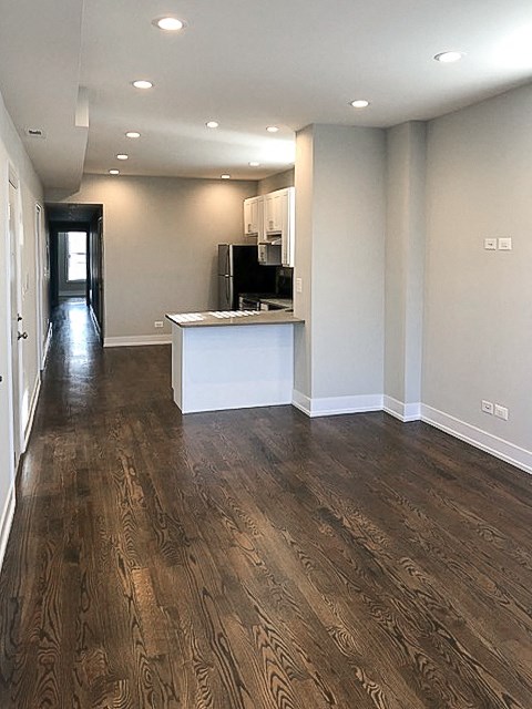 an empty living room and kitchen with wood floors