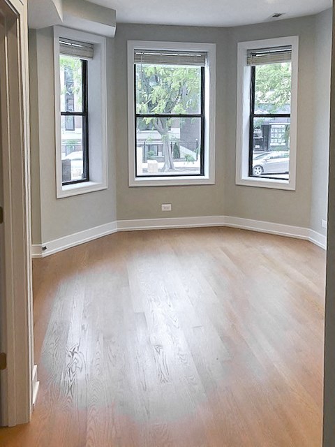an empty room with a wooden floor and three windows