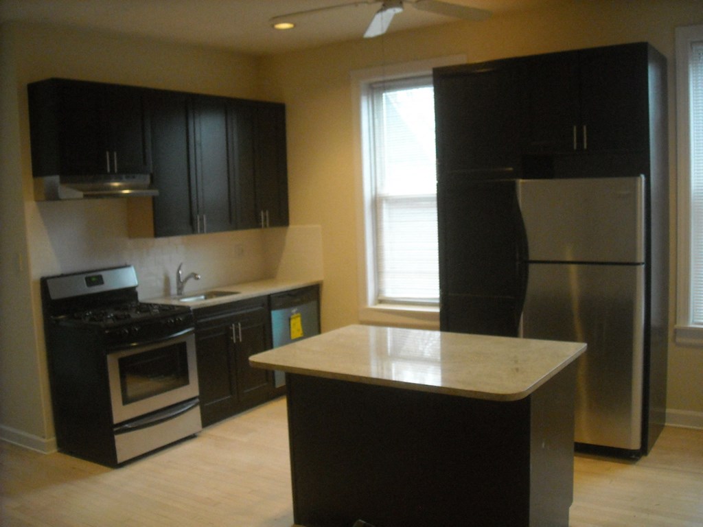 an empty kitchen with stainless steel appliances and black cabinets